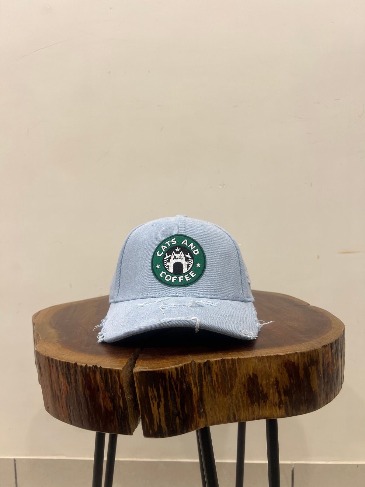 Gray cap with a green logo on a wooden block against a beige wall