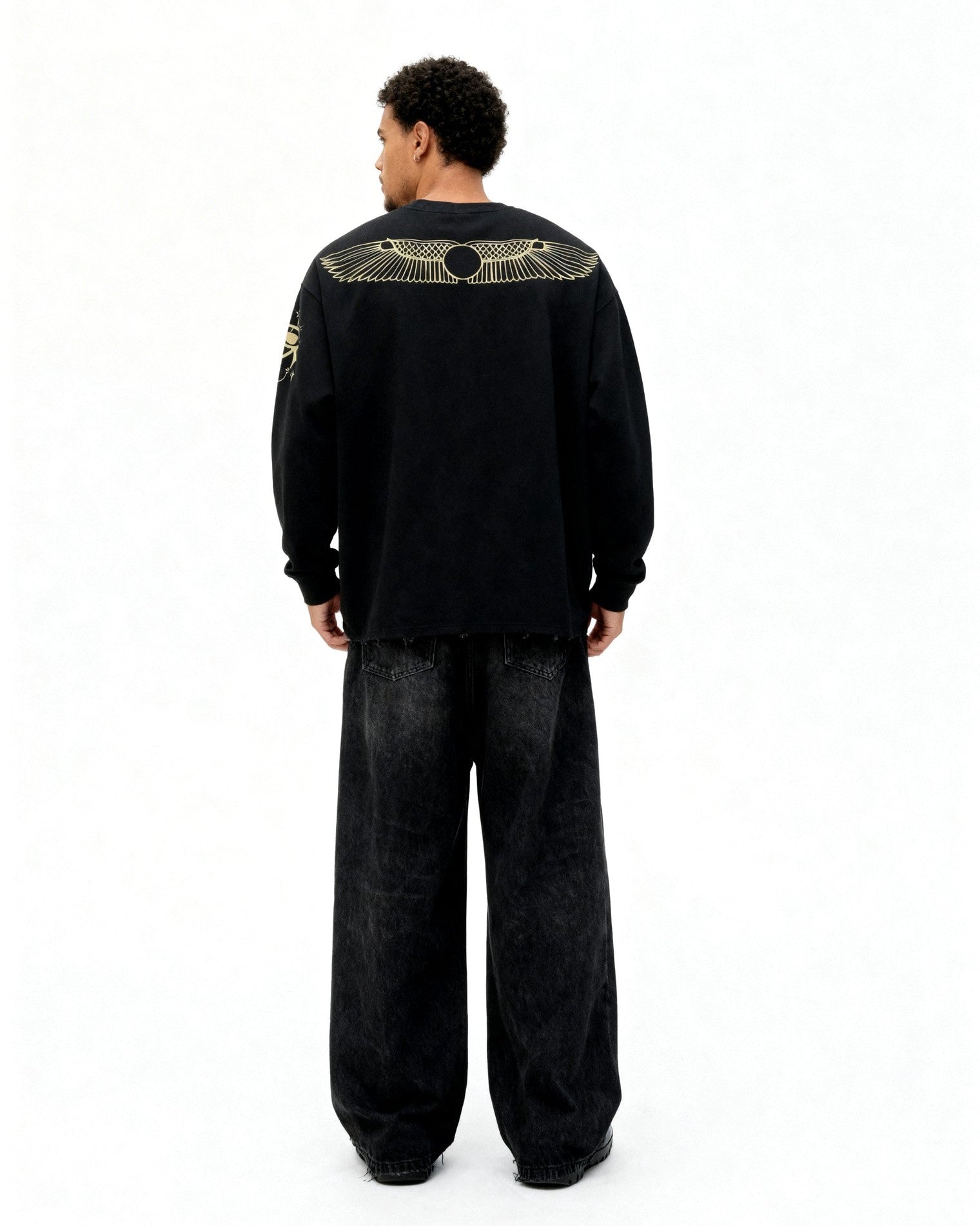 Person wearing a black outfit with gold screen print on the back against a white background